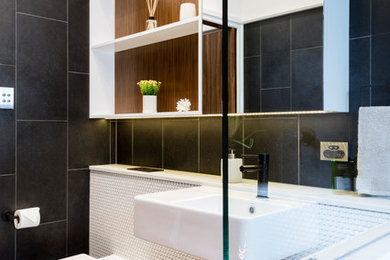Small modern kids bathroom in Brisbane with open cabinets, white cabinets, an open shower, a one-piece toilet, black and white tile, porcelain tile, black walls, porcelain floors, a pedestal sink, wood benchtops, black floor and an open shower.