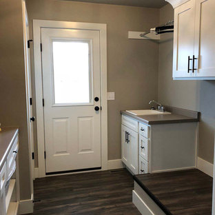 Inspiration for a medium sized modern galley separated utility room in Other with a built-in sink, shaker cabinets, white cabinets, laminate countertops, beige walls, vinyl flooring, a side by side washer and dryer and brown floors.