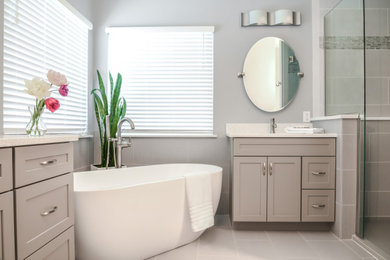 Inspiration for a medium sized traditional ensuite bathroom in St Louis with shaker cabinets, beige cabinets, a freestanding bath, an alcove shower, blue walls, porcelain flooring, a submerged sink, engineered stone worktops, grey floors, a hinged door, white worktops, double sinks and a built in vanity unit.