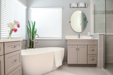 Immagine di una stanza da bagno padronale classica di medie dimensioni con ante in stile shaker, ante beige, vasca freestanding, doccia alcova, pareti blu, pavimento in gres porcellanato, lavabo sottopiano, top in quarzo composito, pavimento grigio, porta doccia a battente, top bianco, due lavabi e mobile bagno incassato