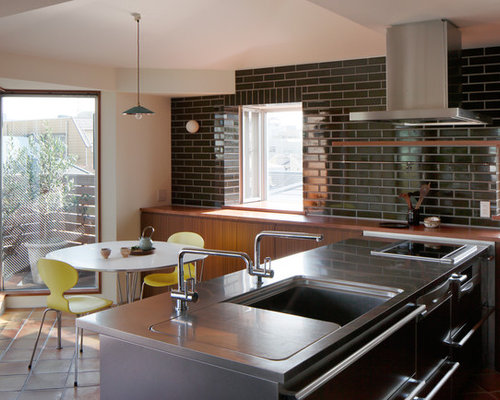 東京都下の小さいコンテンポラリーなダイニングキッチンの写真 (黒いキッチンパネル、一体型シンク、フラットパネル扉のキャビネット、中間色木目調キャビネット、ステンレスカウンター、テラコッタタイルの床、ペニンシュラ型)