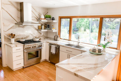 This is an example of a small modern u-shaped kitchen in San Francisco with a double-bowl sink, flat-panel cabinets, white cabinets, engineered stone countertops, white splashback, engineered quartz splashback, stainless steel appliances, light hardwood flooring, a breakfast bar, beige floors and yellow worktops.