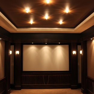 Photo of a large traditional enclosed home cinema in Detroit with brown walls, carpet, a projector screen and beige floors.