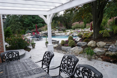 Elegant backyard stamped concrete and custom-shaped natural hot tub photo in Philadelphia