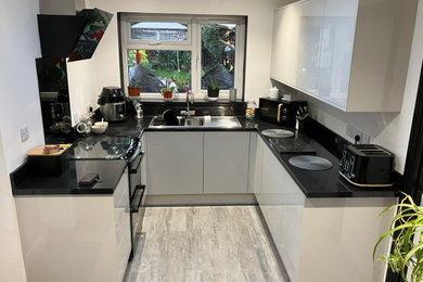 Inspiration for a small modern grey and black u-shaped kitchen in West Midlands with grey cabinets, black splashback, black appliances, laminate floors, no island, grey floors, black worktops and feature lighting.