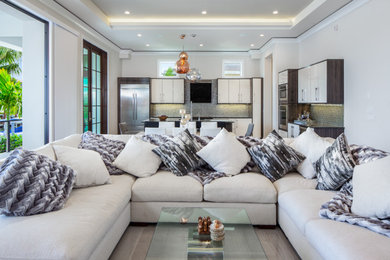 Large modern formal open concept living room in Miami with beige walls, porcelain floors, a ribbon fireplace, a plaster fireplace surround, a wall-mounted tv and grey floor.