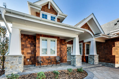 This is an example of a huge craftsman porch design in Other with a roof extension.