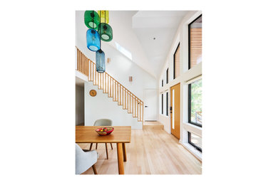 Mid-sized 1960s light wood floor, beige floor and vaulted ceiling entryway photo in New York with white walls and a medium wood front door