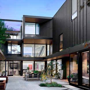 Выдающиеся фото от архитекторов и дизайнеров интерьера: большой, трехэтажный фасад частного дома черного цвета в современном стиле с облицовкой из металла, плоской крышей и зеленой крышей