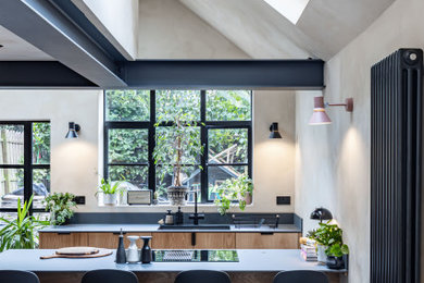 Medium sized urban kitchen/diner in London with an integrated sink, flat-panel cabinets, medium wood cabinets, black appliances, ceramic flooring, an island, grey floors, grey worktops and exposed beams.
