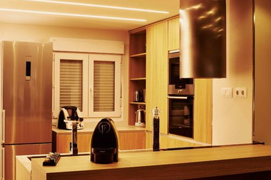 Foto de cocina contemporánea abierta con fregadero bajoencimera, electrodomésticos de acero inoxidable, suelo laminado y península