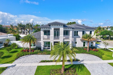 Large transitional gray two-story stucco house exterior photo in Miami with a hip roof and a tile roof
