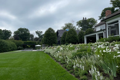 Imagen de jardín tradicional en patio trasero con jardín francés y parterre de flores