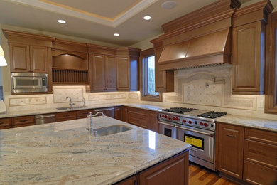 Large transitional l-shaped medium tone wood floor kitchen photo in Denver with an undermount sink, raised-panel cabinets, medium tone wood cabinets, granite countertops, beige backsplash, terra-cotta backsplash, stainless steel appliances and an island