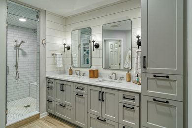 Large transitional master white tile and porcelain tile porcelain tile, brown floor and double-sink bathroom photo in Minneapolis with recessed-panel cabinets, gray cabinets, gray walls, an undermount sink, quartz countertops, a hinged shower door, white countertops and a built-in vanity