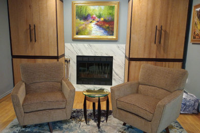 Example of a mid-sized trendy open concept light wood floor and brown floor living room design in Newark with gray walls, a standard fireplace and a stone fireplace
