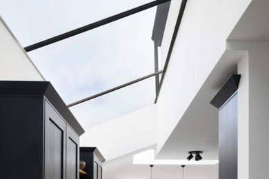 Design ideas for a medium sized contemporary u-shaped kitchen/diner in London with shaker cabinets, grey cabinets, engineered stone countertops, stainless steel appliances, brown floors and white worktops.