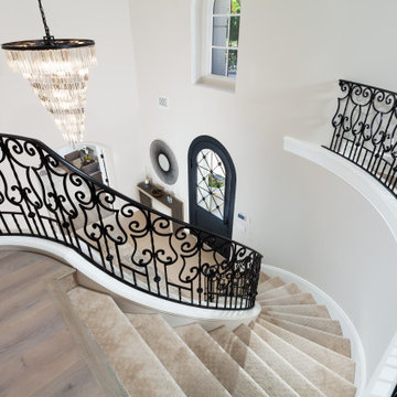 Curved Staircase Detail with Scrolled Iron Railing & Arched Iron Entry Door – Ne