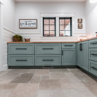Idées déco pour une grand buanderie campagne en L dédiée avec un placard à porte shaker, des portes de placard bleues, un plan de travail en bois, une crédence blanche, une crédence en lambris de bois, un mur blanc, un sol en carrelage de céramique, des machines côte à côte, un sol gris et un plan de travail marron.
