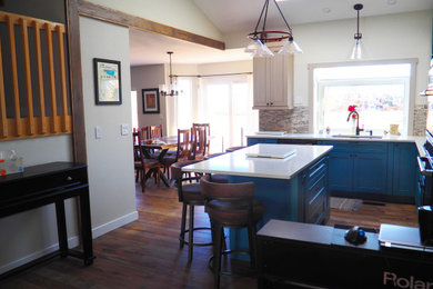 Example of a small l-shaped medium tone wood floor, brown floor and vaulted ceiling eat-in kitchen design in Denver with an undermount sink, shaker cabinets, blue cabinets, quartz countertops, multicolored backsplash, cement tile backsplash, black appliances, an island and white countertops