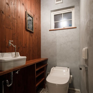 他の地域のインダストリアルスタイルのおしゃれなトイレ・洗面所 (オープンシェルフ、中間色木目調キャビネット、マルチカラーの壁、ベッセル式洗面器、木製洗面台、グレーの床、ブラウンの洗面カウンター) の写真