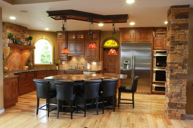Large mountain style l-shaped light wood floor eat-in kitchen photo in Wichita with raised-panel cabinets, distressed cabinets, granite countertops, an island, beige backsplash, ceramic backsplash, stainless steel appliances and an undermount sink