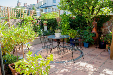 This is an example of a small mediterranean backyard garden in Gloucestershire with concrete pavers.