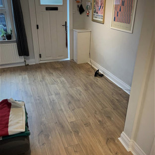 Idee per una piccola porta d'ingresso minimalista con pareti bianche, pavimento in laminato, una porta singola e pavimento marrone