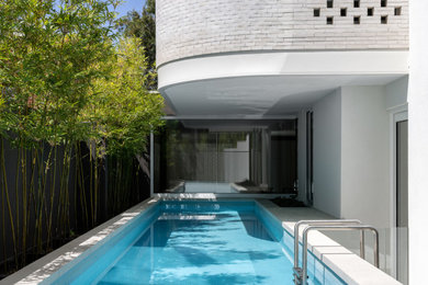Mid-sized contemporary side yard rectangular lap pool in Melbourne with with privacy feature.