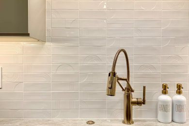 Example of a large minimalist l-shaped porcelain tile and beige floor kitchen pantry design in Other with a single-bowl sink, flat-panel cabinets, beige cabinets, quartzite countertops, white backsplash, porcelain backsplash, stainless steel appliances, an island and beige countertops