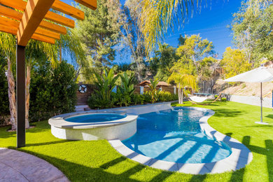 Imagen de piscina natural mediterránea de tamaño medio tipo riñón en patio trasero con paisajismo de piscina y losas de hormigón