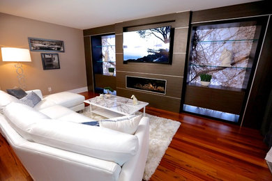 Inspiration for a mid-sized modern formal and enclosed medium tone wood floor living room remodel in Toronto with beige walls, a ribbon fireplace, a wood fireplace surround and a media wall