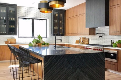 This is an example of a contemporary l-shaped kitchen in Los Angeles with flat-panel cabinets, stainless steel cabinets, white splashback, subway tile splashback, stainless steel appliances and with island.