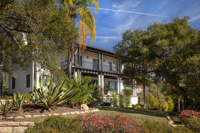 Example of a tuscan white stucco house exterior design in Santa Barbara with a tile roof and a red roof