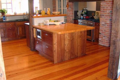 Inspiration for a mid-sized transitional medium tone wood floor and brown floor kitchen remodel in St Louis with a drop-in sink, beaded inset cabinets, stainless steel appliances, an island and wood countertops