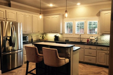 Example of a mid-sized minimalist u-shaped light wood floor eat-in kitchen design in Austin with an undermount sink, raised-panel cabinets, white cabinets, limestone countertops, white backsplash, ceramic backsplash, stainless steel appliances and an island