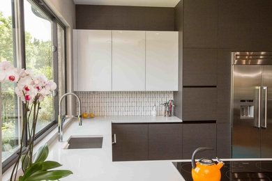 Eat-in kitchen - large contemporary u-shaped painted wood floor and brown floor eat-in kitchen idea in Austin with an undermount sink, flat-panel cabinets, brown cabinets, quartz countertops, white backsplash, subway tile backsplash, stainless steel appliances, a peninsula and white countertops