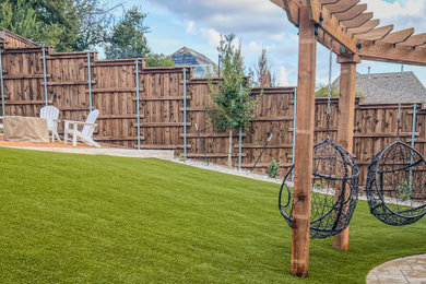 This is an example of a mid-sized modern drought-tolerant and full sun backyard river rock and wood fence landscaping in Dallas with a pergola for summer.