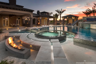 Inspiration for an expansive contemporary backyard custom-shaped infinity pool in Phoenix with natural stone pavers.