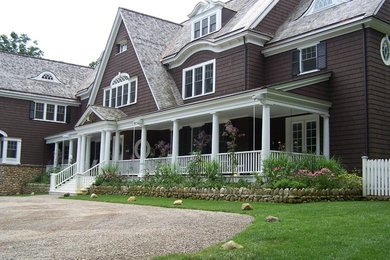 Large three-storey brown house exterior in New York with wood siding, a gable roof and a shingle roof.