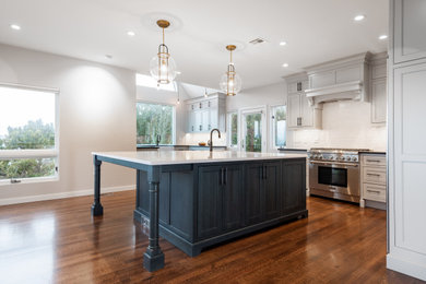 Design ideas for an expansive transitional l-shaped eat-in kitchen in Providence with a farmhouse sink, beaded inset cabinets, white cabinets, quartzite benchtops, white splashback, ceramic splashback, stainless steel appliances, dark hardwood floors, with island, brown floor and white benchtop.