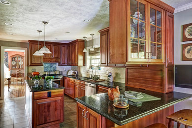 Inspiration for a large timeless u-shaped porcelain tile and brown floor enclosed kitchen remodel in Other with an undermount sink, raised-panel cabinets, medium tone wood cabinets, granite countertops, beige backsplash, porcelain backsplash, stainless steel appliances and an island