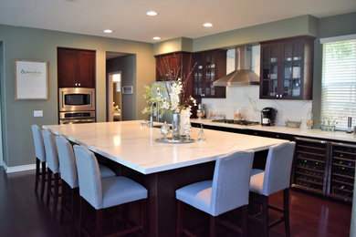 Inspiration for a mid-sized contemporary l-shaped dark wood floor and brown floor open concept kitchen remodel in Los Angeles with an island, shaker cabinets, dark wood cabinets, marble countertops, white backsplash, marble backsplash, stainless steel appliances, white countertops and an undermount sink
