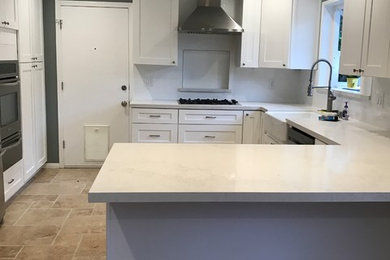 Kitchen - mid-sized contemporary u-shaped travertine floor kitchen idea in San Francisco with a farmhouse sink, shaker cabinets, white cabinets, quartz countertops, white backsplash and subway tile backsplash