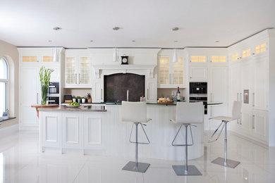 Inspiration for a large transitional eat-in kitchen in Other with an undermount sink, beaded inset cabinets, granite benchtops, black splashback, stone slab splashback, black appliances, porcelain floors, with island and white floor.