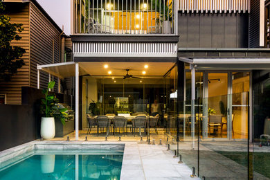 Design ideas for a mid-sized contemporary backyard rectangular lap pool in Brisbane with a water feature and natural stone pavers.