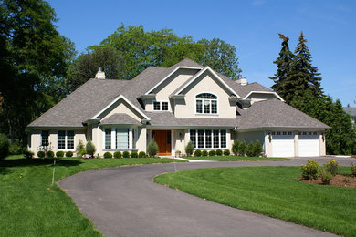 Example of a transitional gray two-story stucco house exterior design in Chicago with a clipped gable roof and a shingle roof