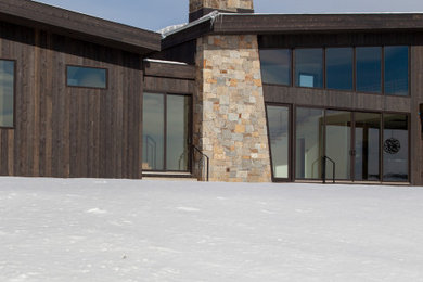 Large trendy black split-level wood house exterior photo in New York with a shed roof and a green roof