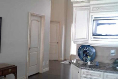 Example of a large dark wood floor enclosed kitchen design in Calgary with raised-panel cabinets, white cabinets and stainless steel appliances