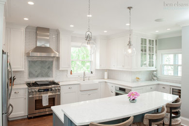 Eat-in kitchen - mid-sized traditional l-shaped medium tone wood floor eat-in kitchen idea in Cincinnati with a farmhouse sink, recessed-panel cabinets, white cabinets, quartzite countertops, white backsplash, subway tile backsplash, stainless steel appliances and an island